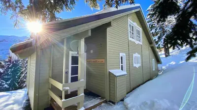 a small green building in the snow with the sun shining at Les Chalets de Flaine Hameau - maeva Home - Chalet 4 pièces 6 personnes - Prestige MAE-3971 in Flaine