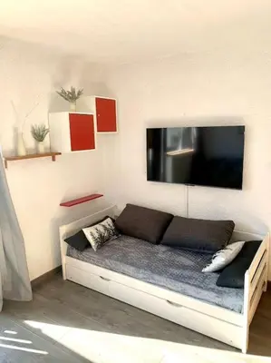 a couch in a room with a tv on the wall at Studio Flaine à coté des pistes in Arâches-la-Frasse