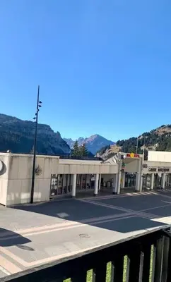 a building on a street with mountains in the background at Studio Flaine à coté des pistes in Arâches-la-Frasse