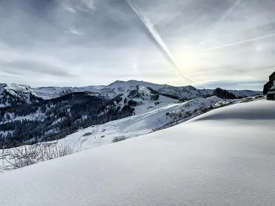 a view of a snow covered mountain with the sun in the sky at Ski1600 - GrandMassif in Samoëns
