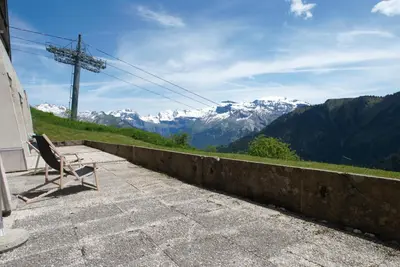a bench sitting on a balcony with a view of mountains at Ski1600 - GrandMassif in Samoëns
