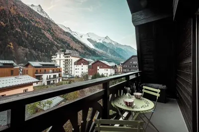 a balcony with a table and chairs and mountains at Vertice - Center Chamonix Mont-Blanc View in Chamonix-Mont-Blanc
