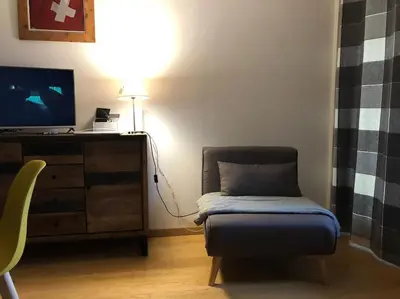 a living room with a chair and a tv at Les montagnes sur le balcon in Chamonix-Mont-Blanc