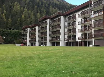 a large building with a grass field in front of it at Les montagnes sur le balcon in Chamonix-Mont-Blanc