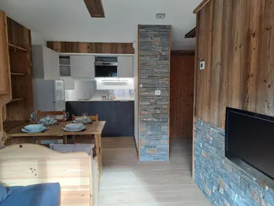 a kitchen and living room with a table and a tv at Appartement équipé centre Carroz et garage in Arâches-la-Frasse