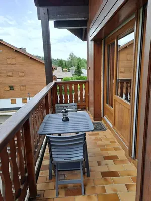 a wooden deck with a table and chairs on a balcony at Appartement équipé centre Carroz et garage in Arâches-la-Frasse