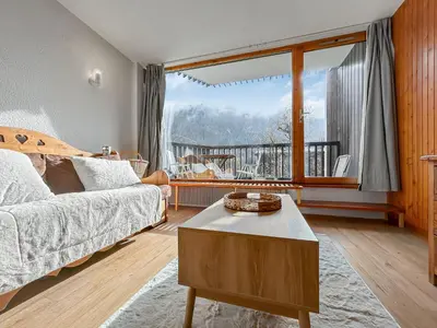 a living room with a bed and a large window at Vue Mont Blanc, balcon et parking privé in Chamonix-Mont-Blanc