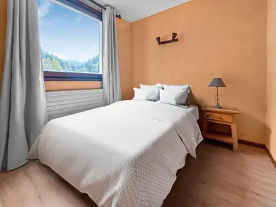 a bedroom with a white bed and a window at Vue Mont Blanc, balcon et parking privé in Chamonix-Mont-Blanc