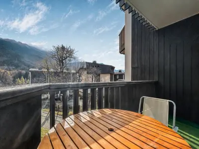 a wooden table on a balcony with a view at Vue Mont Blanc, balcon et parking privé in Chamonix-Mont-Blanc