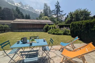 a table and chairs in a yard with mountains at Appartement Sérénité - Welkeys in Chamonix-Mont-Blanc