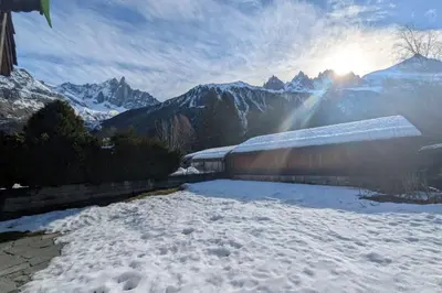a snow covered yard with the sun in the mountains at Appartement Sérénité - Welkeys in Chamonix-Mont-Blanc