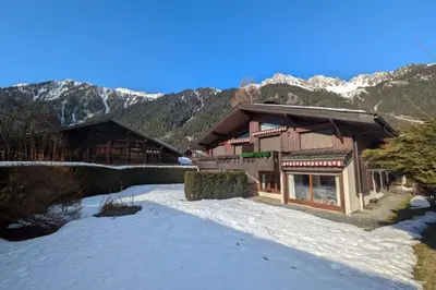a house in the snow with mountains in the background at Appartement Sérénité - Welkeys in Chamonix-Mont-Blanc