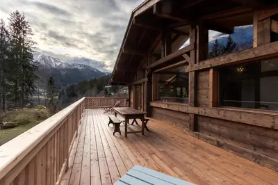 a wooden deck with a bench on a house at Chalet des Eaux Rousses -Renove -Prive - Vues 360 Mont Blanc in Les Houches