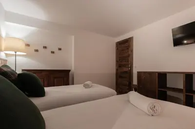 a bedroom with two beds and a tv on the wall at Chalet des Eaux Rousses -Renove -Prive - Vues 360 Mont Blanc in Les Houches