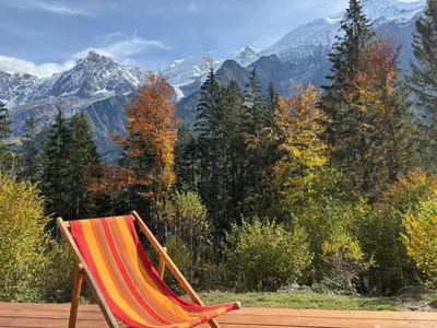 a chair sitting on a deck with a view of mountains at Chalet des Eaux Rousses -Renove -Prive - Vues 360 Mont Blanc in Les Houches