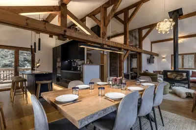 a dining room and living room with a wooden table and chairs at Chalet des Eaux Rousses -Renove -Prive - Vues 360 Mont Blanc in Les Houches
