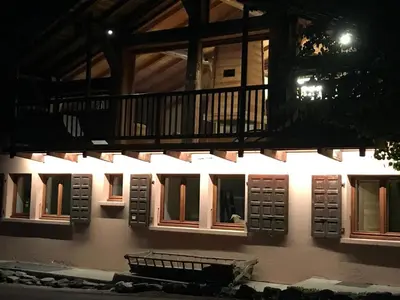 a building with lights on the side of it at night at La Ferme du Mont in Servoz