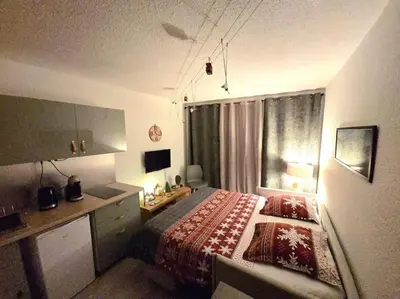a bedroom with a bed and a desk and a window at Studio avec balcon vue MontBlanc et parking gratuit le nid daigle in Chamonix-Mont-Blanc