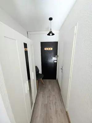 a hallway with a black door and a room with a wooden floor at Studio avec balcon vue MontBlanc et parking gratuit le nid daigle in Chamonix-Mont-Blanc