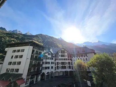 a large building with mountains in the background at Studio avec balcon vue MontBlanc et parking gratuit le nid daigle in Chamonix-Mont-Blanc