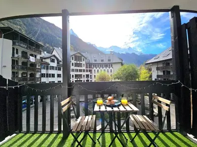 a table on a balcony with a view of the mountains at Studio avec balcon vue MontBlanc et parking gratuit le nid daigle in Chamonix-Mont-Blanc