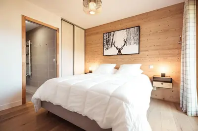 a bedroom with a large white bed and wooden walls at Appartement Margot - All the comforts with a view of Mont Blanc in Combloux