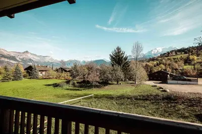 a balcony with a view of a field and mountains at Appartement Margot - All the comforts with a view of Mont Blanc in Combloux