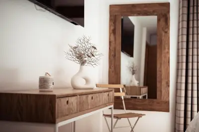 a room with a mirror and a table with a vase at Appartement Margot - All the comforts with a view of Mont Blanc in Combloux