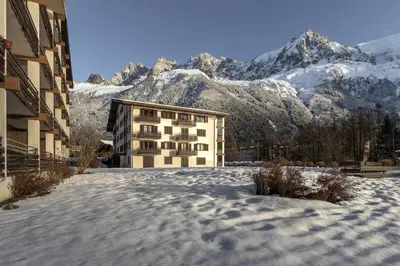 a building in the snow with mountains in the background at Cristal des Glaces - Balcon avec vue imprenable in Chamonix-Mont-Blanc