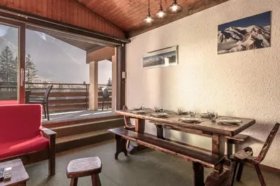 a dining room with a table and a red chair at Cristal des Glaces - Balcon avec vue imprenable in Chamonix-Mont-Blanc