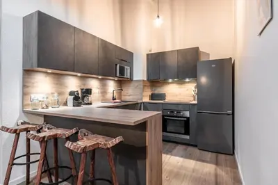a kitchen with a refrigerator and a counter with stools at Cristal des Glaces - Balcon avec vue imprenable in Chamonix-Mont-Blanc