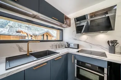 a kitchen with blue cabinets and a sink and a window at Chalet Ikigai Chamonix - by EMERALD STAY in Chamonix-Mont-Blanc