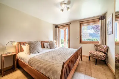 a bedroom with a bed and a chair and a window at Chalet Ibex Les Houches Chamonix - by EMERALD STAY in Les Houches