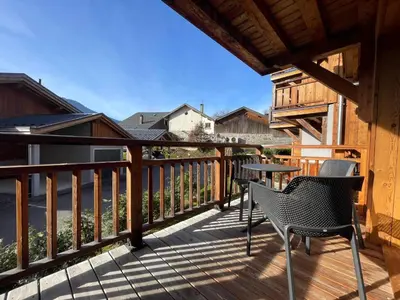 a deck with two chairs and a table on it at Appartement lumineux avec balcons, WIFI et parking à Samoëns - FR-1-624-172 in Samoëns