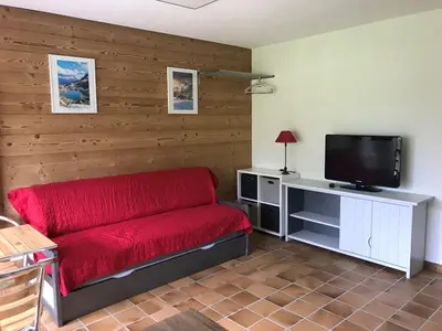 a living room with a red couch and a flat screen tv at Studio 4 pers, skis aux pieds, lave-vaisselle, lave-linge, balcon - FR-1-572-299 in Arâches-la-Frasse