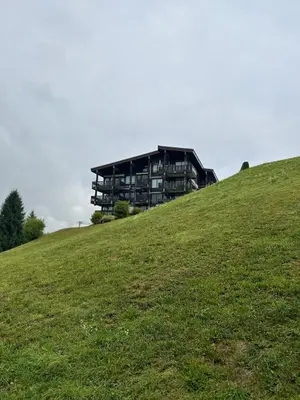 a building on top of a grassy hill at Blanches Alpes Appartement Megève in Megève