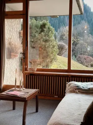 a bedroom with a large window and a table and a bed at Blanches Alpes Appartement Megève in Megève
