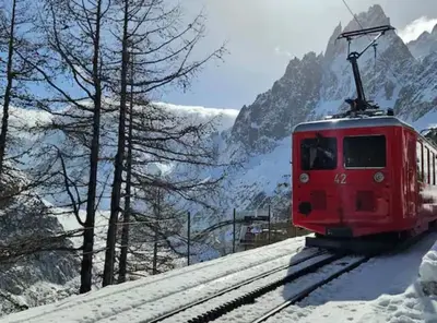 a red train traveling down the tracks in the snow at Duplex 4 pers vue MontBlanc , Grands Montets in Chamonix-Mont-Blanc