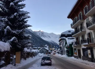 a snow covered street with a car parked next to a building at Duplex 4 pers vue MontBlanc , Grands Montets in Chamonix-Mont-Blanc
