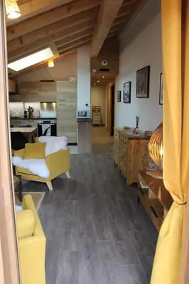 a living room with a yellow couch and a kitchen at Appartement de standing Chalet Bostan in Samoëns