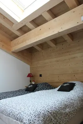 a bedroom with a large bed with a wooden ceiling at Appartement de standing Chalet Bostan in Samoëns