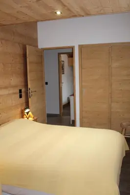 a bedroom with a large bed and wooden walls at Appartement de standing Chalet Bostan in Samoëns