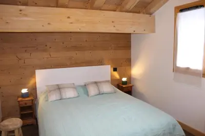 a bedroom with a bed with a wooden wall at Appartement de standing Chalet Bostan in Samoëns