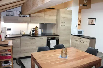 a kitchen with a wooden table and chairs in it at Appartement de standing Chalet Bostan in Samoëns