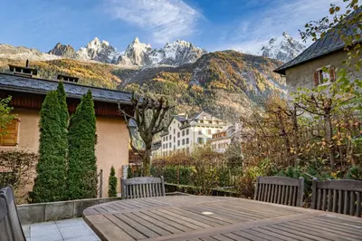 a patio with a table and chairs and mountains at Alpine Garden - Truly hidden gem with sunny garden in Chamonix town center in Chamonix-Mont-Blanc