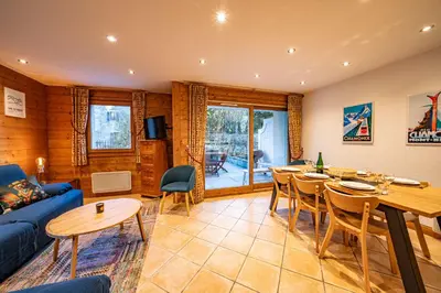 a living room with a blue couch and a table and chairs at Alpine Garden - Truly hidden gem with sunny garden in Chamonix town center in Chamonix-Mont-Blanc
