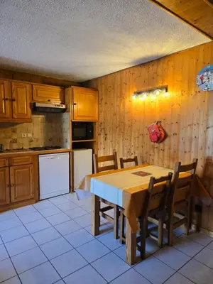 a kitchen with a table and chairs and a refrigerator at Chaleureux refuge thermal in Saint-Gervais-les-Bains