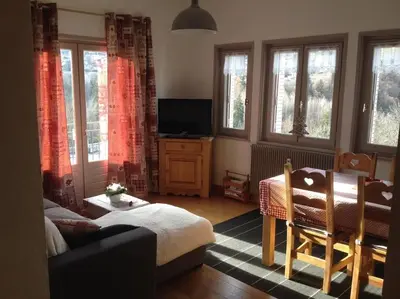 a living room with a couch and a tv and windows at Appart cosy et lumineux au cœur de Saint Gervais in Saint-Gervais-les-Bains