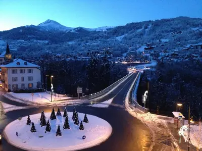 a street with christmas trees in the snow at night at Appart cosy et lumineux au cœur de Saint Gervais in Saint-Gervais-les-Bains