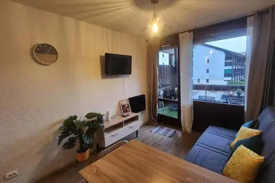 a living room with a blue couch and a tv at Cocon Face au MontBlanc in Sallanches
